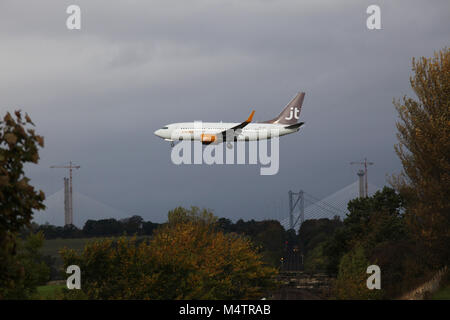 Momenti prima di atterrare un jt boeing 737 jet OY-JTT vola sopra la Edinburgh di fife linea ferroviaria con un treno che si avvicina a distanza Foto Stock