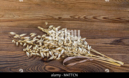 Cereali secchi orecchie su di un tavolo di legno. Decorative dei picchi di avena su marrone vintage background. Foto Stock