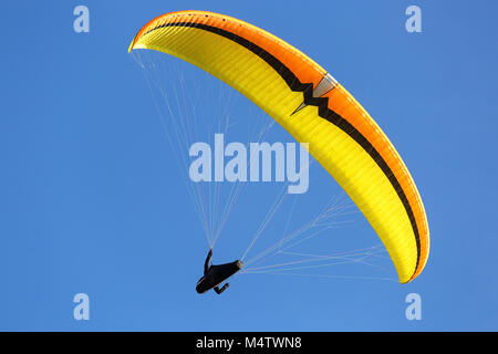 Sky Diver con giallo arancione parachute galleggianti in aria Foto Stock