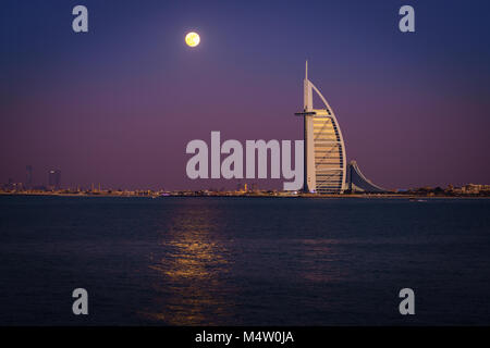Dubai, UAE, Dicembre 13, 2016: la luna piena è in aumento su Burj Al Arab - il mondo solo 7 stelle lusso Foto Stock