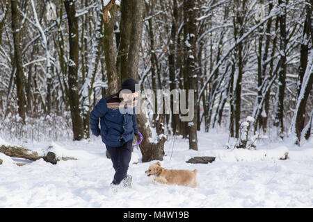 L'uomo gioca con il cane nella foresta di neve Foto Stock