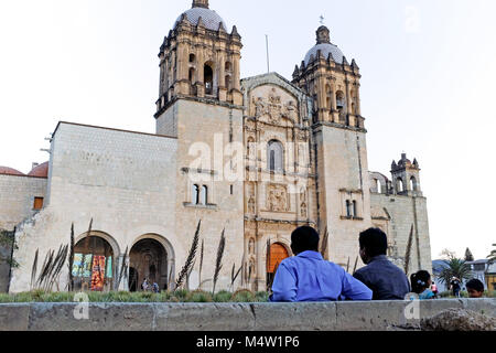 Due uomini siedono nella piazza davanti al punto di riferimento del Templo de Santo Domingo de Guzman in Oaxaca, Messico al tramonto. Foto Stock