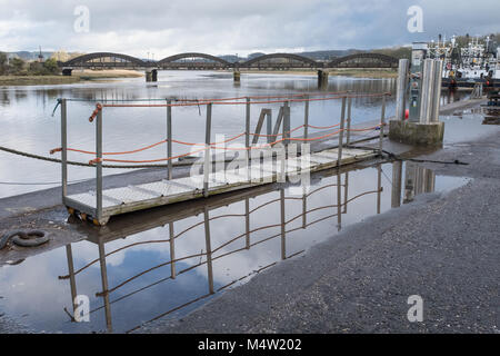 Una vista del porto di Kirkcudbright, in Scozia, con una passerella in primo piano e il fiume Dee e il ponte di Kirkcudbright in lontananza. Foto Stock