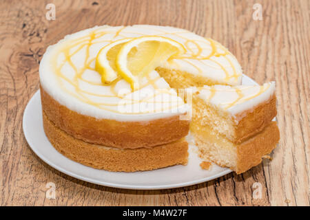 Una pioggerellina di limone torta con una fetta rimosso Foto Stock