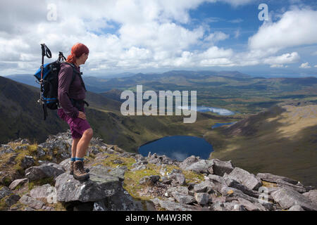 Escursionista guardando sopra Coomloughra Lough da Beenkeragh, il MacGillycuddy Reeks, nella contea di Kerry, Irlanda. Foto Stock