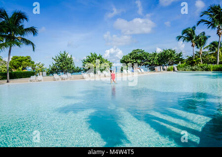 Woman in Red costume salta con entusiasmo in una delle più grandi piscine nei Caraibi. Foto Stock