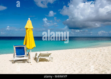 Ombrello giallo e blu lettino su una bellissima spiaggia di sabbia bianca di Anguilla. Foto Stock