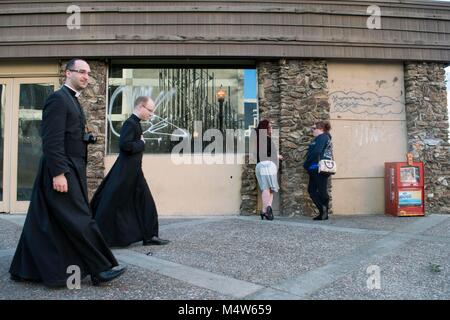 Due donne chat in Sacramento mentre i sacerdoti a piedi giù per la strada. Foto Stock