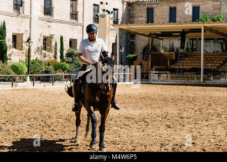 Cordoba, Spagna - 12 Aprile 2017: Cavallo cavaliere a cavallo di un marrone cavallo andaluso noto anche come puro Cavallo Spagnolo nella storica Royal maneggio di Cordoba. Foto Stock