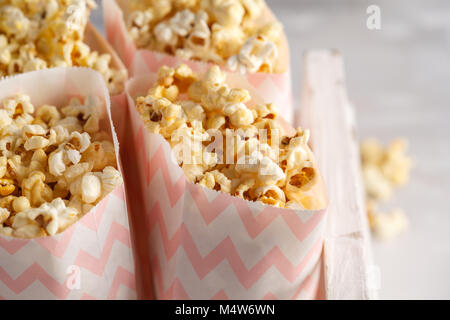 Golden caramello pop corn in sacchetti di carta in un bianco scatola di legno. Foto Stock