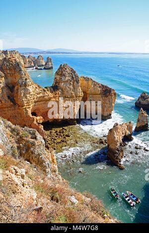 Vista in elevazione delle coste frastagliate e scogliere con tour di barche in primo piano, Ponta da Piedade, Algarve, Portogallo, dell'Europa. Foto Stock