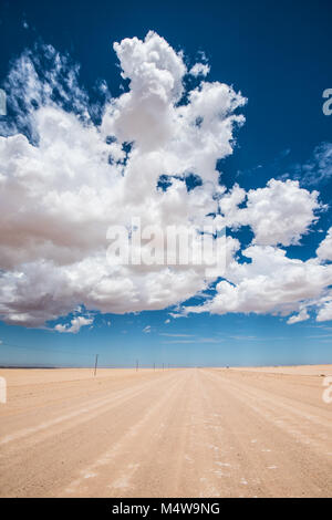 Immagine vibrante della strada nel deserto e blu cielo nuvoloso Foto Stock