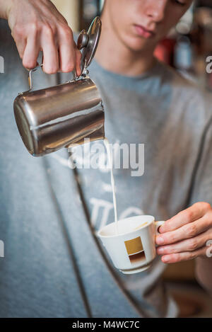 Versare il latte in una tazza di caffè Foto Stock