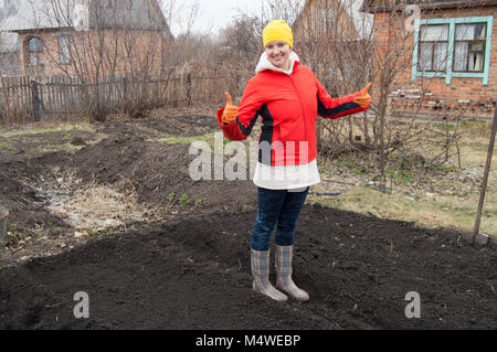 Lunghezza completa il ritratto di una donna sorridente giardiniere che mostra il pollice in alto Foto Stock