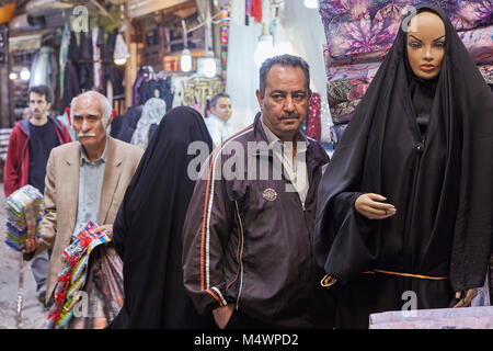 Tehran, Iran - 29 Aprile 2017: un uomo maturo sorge accanto al manichino di una donna musulmana in un chador nero nel bazar orientale. Foto Stock