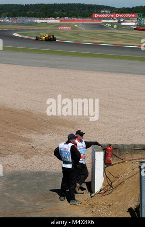 Due Formula 1 marshalls in piedi accanto a ghiaia Foto Stock