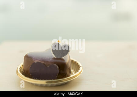 Voglia di torta al cioccolato a forma di cuore su di un tavolo di legno Foto Stock