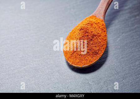 Shichimi pepe in cucchiaio di legno sulla pietra nera piastra Foto Stock