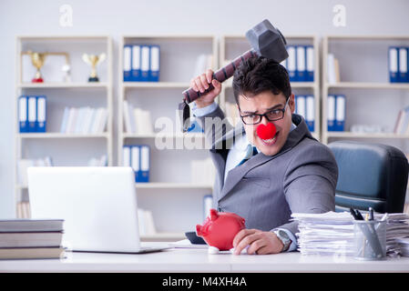 Clown imprenditore con un salvadanaio e un martello Foto Stock