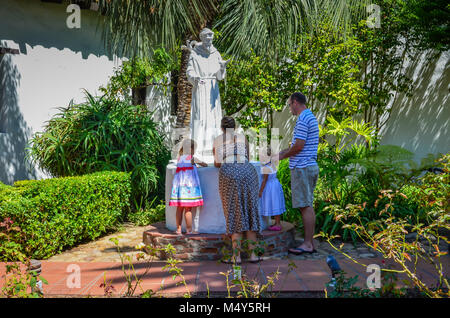 Cali di famiglia dita in Wishing Well nel giardino di missione Basilica di San Diego de Alcalá a San Diego, CA. Foto Stock