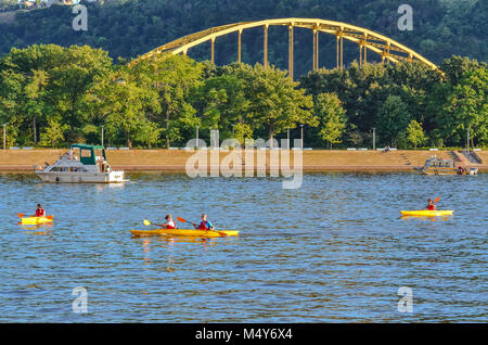 PIttsburgh, PA, Stati Uniti d'America. Quattro giallo kayak sul fiume Ohio nella parte anteriore di un ponte di colore giallo. Foto Stock
