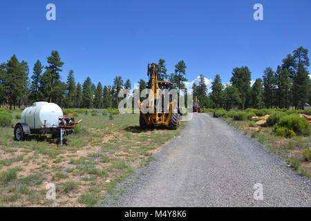 Una vista di caricatori frontali e un serbatoio di acqua sono visibili sul sentiero Greenway. Tra il 10 agosto al 10 settembre 2016 la Greenway sentiero tra il Teatro IMAX area di parcheggio in Tusayan e centro strada nel Parco Nazionale del Grand Canyon verrà chiusa mentre il Grand Canyon Trail dell equipaggio installa asfalto. Il tratto del sentiero a nord della strada del centro non saranno interessati. Mentre il sentiero chiusura è in effetti, i ciclisti e gli escursionisti possono cavalcare la navetta Tusayan (percorso viola) che è dotato di supporto per bicicletta rack. La navetta collega Tusayan con il bordo meridionale Visitor Center, a 20 minuti in ogni modo. Foto Stock