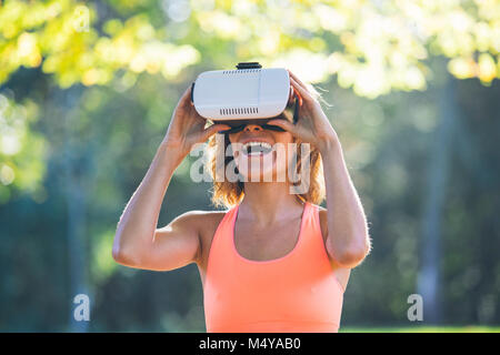 Giovane donna a praticare yoga nella natura con casco VR Foto Stock