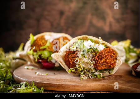 Falafel in sfere di pita con salsa tahini sul pannello di legno Foto Stock