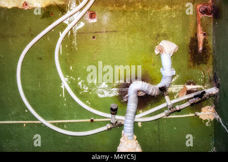 Acqua e tubi di cucitore sullo sfondo del vecchio muro. Riparazione in casa. Collegamento del metallo-tubi in plastica Foto Stock