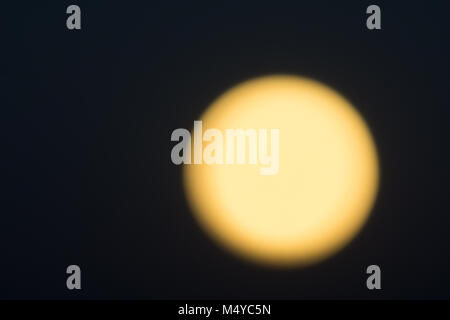 Bagliore dorato della luna piena contro il nero cielo notturno. Foto Stock