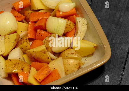 Materie carota, cipolla e patate in un piatto di ceramica preparato per la tostatura Foto Stock