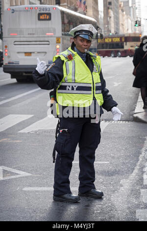 Una femmina di cop di traffico dirigere il traffico sulla Quinta Avenue nel centro di Manhattan, New York Citysafety giubbotto, fischio, colpi, soffiaggio, fuori all'aperto, fuori Foto Stock