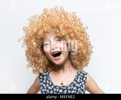 Indossa una parrucca bionda e divertente l'espressione del viso ragazza asiatica Foto Stock