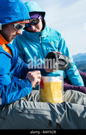 L uomo e la donna l'impostazione di campeggio e la cottura di congelare alimenti secchi in inverno, White Mountains, New Hampshire, STATI UNITI D'AMERICA Foto Stock