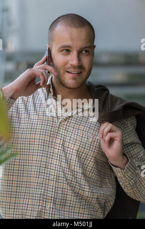 Bello elegante imprenditore parlando al telefono in ufficio Foto Stock