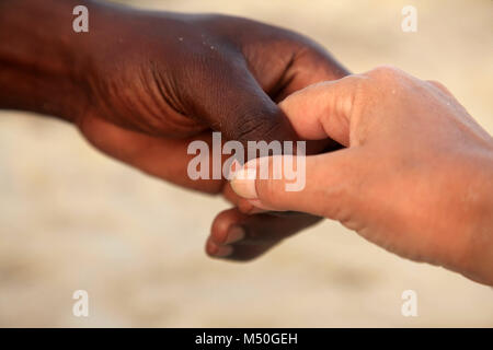 Le mani di una donna caucasica e un uomo africano Foto Stock