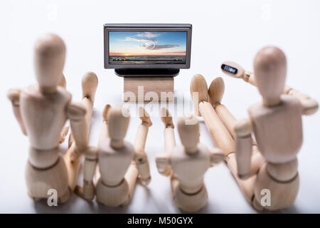 Angolo di Alta Vista del manichino di legno famiglia seduta sul pavimento per guardare video Foto Stock