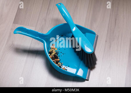 Lo sporco raccolto in plastica polvere di spazzamento Pan e la spazzola sopra il pavimento di legno duro Foto Stock