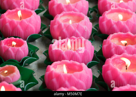 Dettaglio delle candele accese nella forma di un fiore in un monastero buddista. Foto Stock