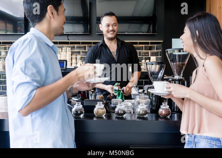 Allegro giovane barista la pulizia della macchina per il caffè mentre si parla Foto Stock