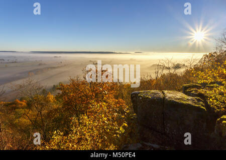 Sole che splende su una valle con la nebbia in autunno Foto Stock