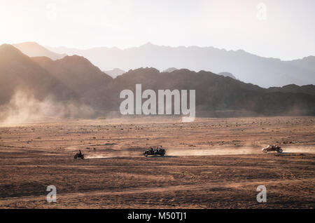 Buggy e ATV quads gare nel deserto del Sinai al tramonto. Paesaggio egiziano con veicoli fuoristrada e polvere di strada sterrata. Sharm el Sheikh, Egitto. Foto Stock