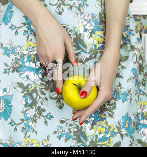 Donna di mani tenendo una mela verde. Moda foto d'arte. Bellezza, gioielli e manicure Foto Stock