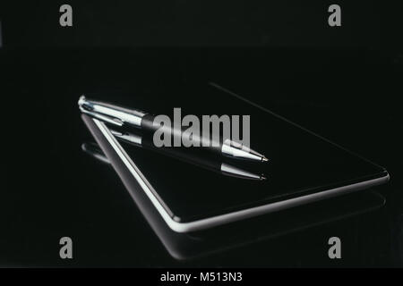 Close-up shot della tavoletta digitale con la penna sulla superficie nera Foto Stock
