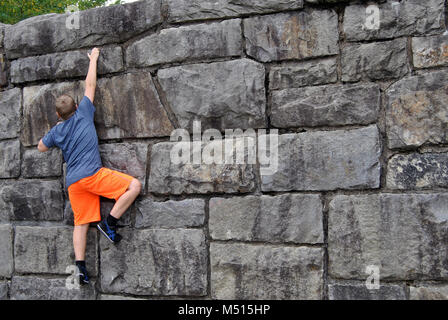 Ragazzo scalare una parete di roccia Foto Stock