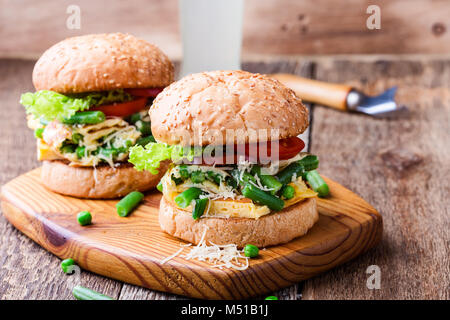 Frittata di uova burger con fagiolini e piselli riempimento rustico sul tagliere di legno, deliziosi snack vegetariano in stile rurale Foto Stock