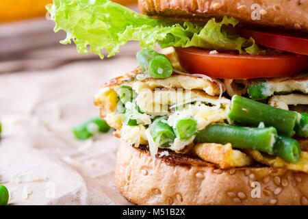 Frittata di uova burger con fagiolini e piselli riempimento sulla tavola in legno rustico, delizioso spuntino picnic in stile rurale Foto Stock