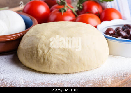 Rendendo gourmet pizza con i germogli topping. Materie impasto per pizza con ingredienti, close-up Foto Stock