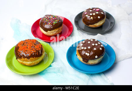 Decorate le ciambelle su piastre colorate vista superiore Foto Stock