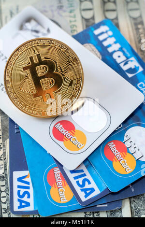 Token Bitcoin sulla sommità di VISA e MasterCard carte di credito e banconote americane Foto Stock